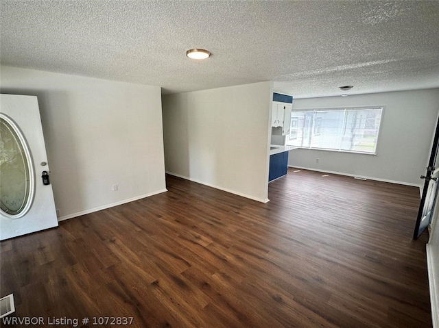 unfurnished living room with a textured ceiling and dark hardwood / wood-style floors