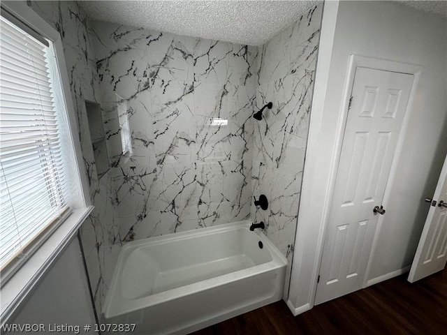 bathroom with hardwood / wood-style floors, a healthy amount of sunlight, washtub / shower combination, and a textured ceiling