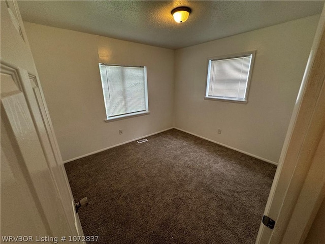 carpeted spare room with a textured ceiling