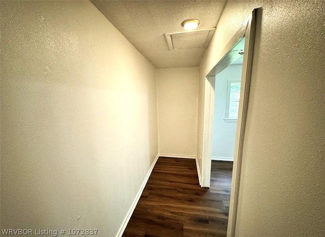 corridor with dark hardwood / wood-style flooring and a textured ceiling