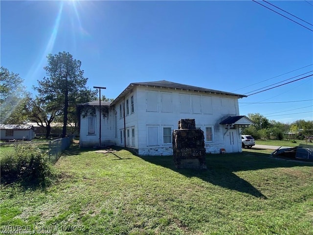 view of side of property featuring fence and a yard