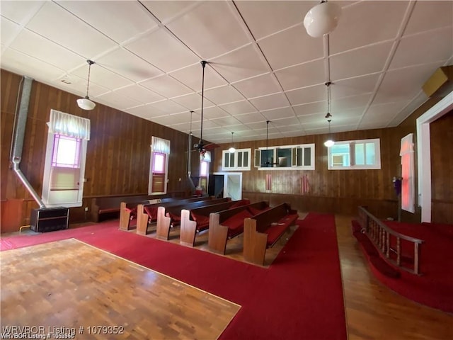 game room with a drop ceiling and wood walls