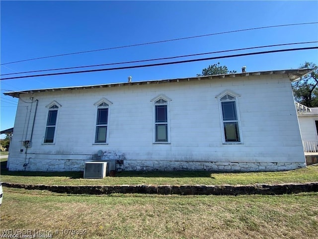 view of side of property featuring central AC unit and a lawn