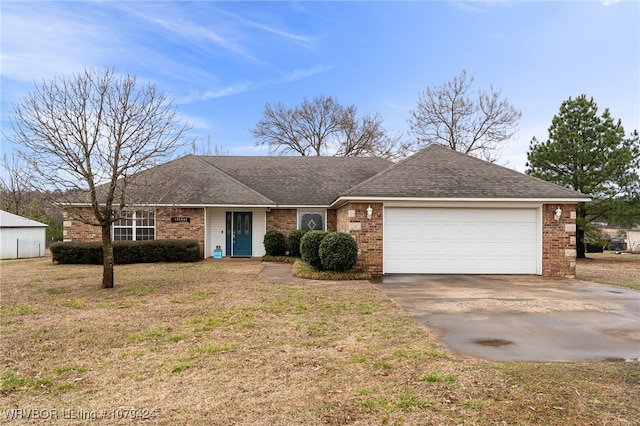 ranch-style home featuring a garage, driveway, brick siding, and a front yard