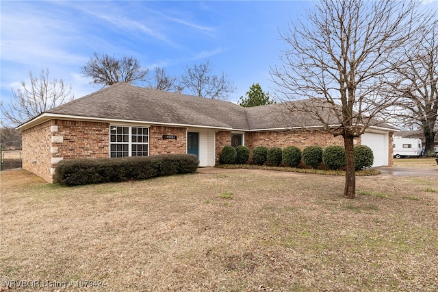 single story home with a front lawn, brick siding, an attached garage, and roof with shingles