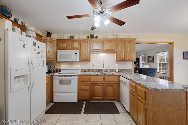 kitchen featuring white appliances, light tile patterned floors, a peninsula, light stone countertops, and a sink