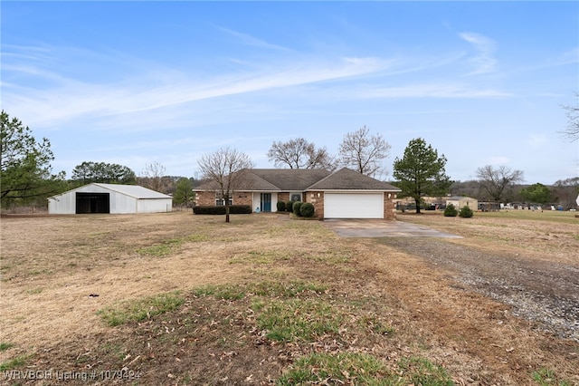 single story home featuring a garage, brick siding, concrete driveway, and an outbuilding