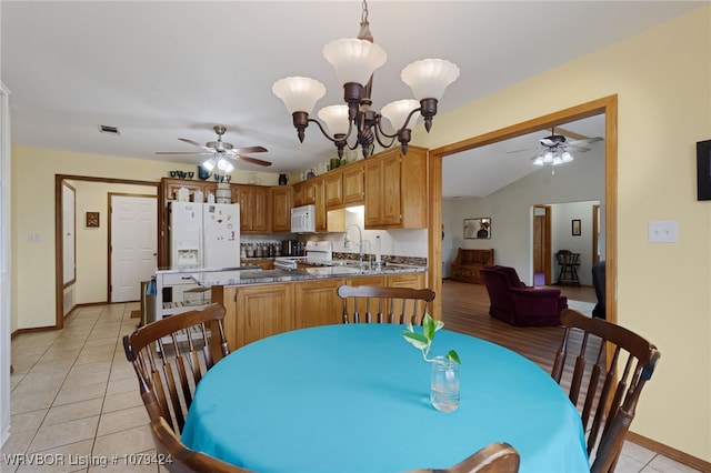 dining room featuring light tile patterned floors, lofted ceiling, visible vents, baseboards, and ceiling fan with notable chandelier