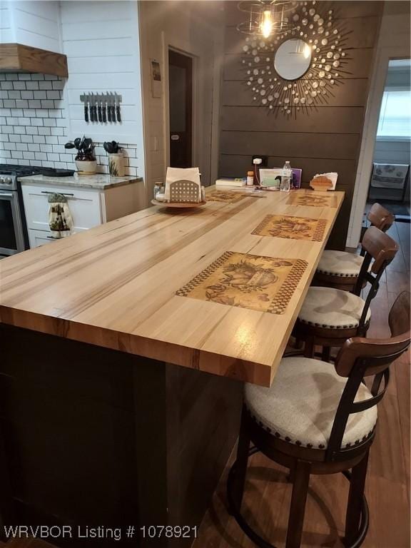 bar featuring white cabinetry, premium range hood, tasteful backsplash, and butcher block countertops