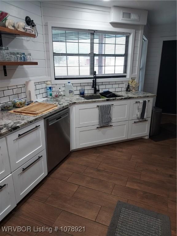 kitchen with light stone counters, stainless steel dishwasher, sink, and white cabinets