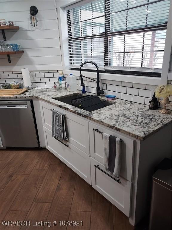 kitchen with sink, dark hardwood / wood-style flooring, dishwasher, light stone countertops, and white cabinets