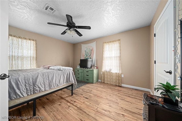 bedroom featuring ceiling fan, light hardwood / wood-style floors, and a textured ceiling