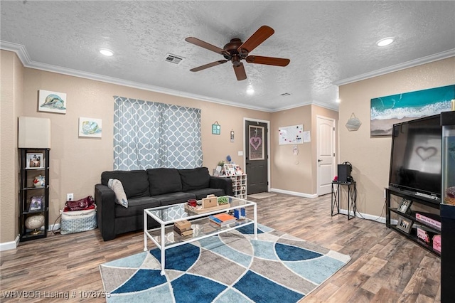 living room with wood-type flooring, ornamental molding, and a textured ceiling