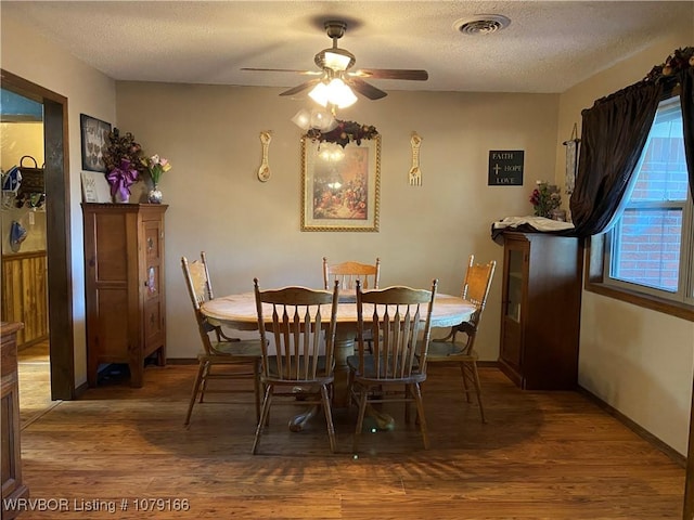 dining room featuring a textured ceiling, visible vents, and wood finished floors