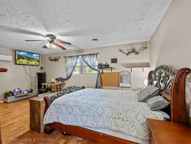 23805 270th Hwy, Howe, OK 74940 - bedroom featuring wood finished floors, a wall mounted AC, a ceiling fan, and a textured ceiling