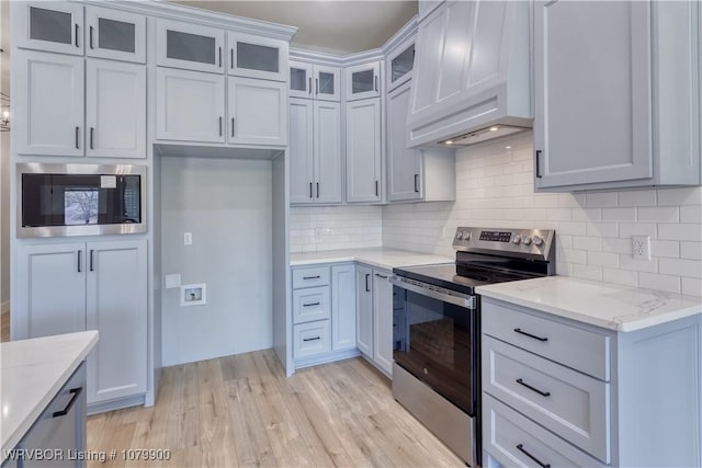 407 W Beech St, Greenwood, AR 72936 - kitchen with stainless steel appliances, custom exhaust hood, light wood-style flooring, tasteful backsplash, and glass insert cabinets