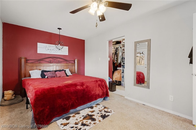 bedroom with a spacious closet, light colored carpet, a closet, and ceiling fan