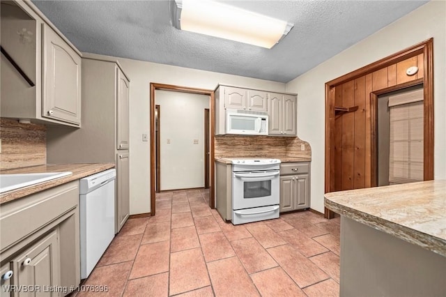 kitchen with white appliances, sink, decorative backsplash, light tile patterned floors, and a textured ceiling