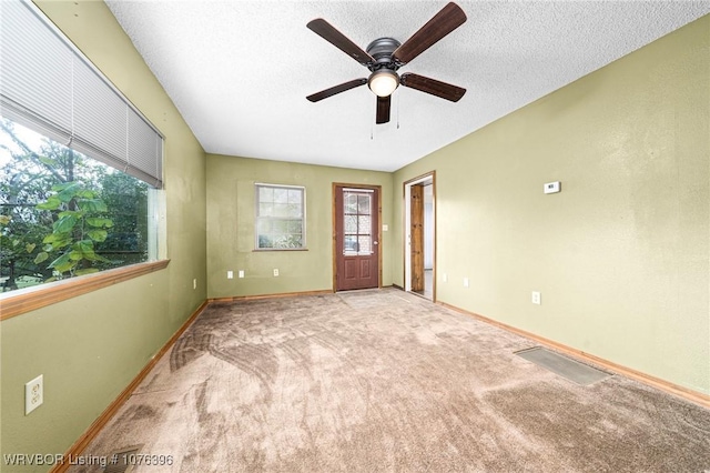 empty room featuring ceiling fan, light colored carpet, and a textured ceiling