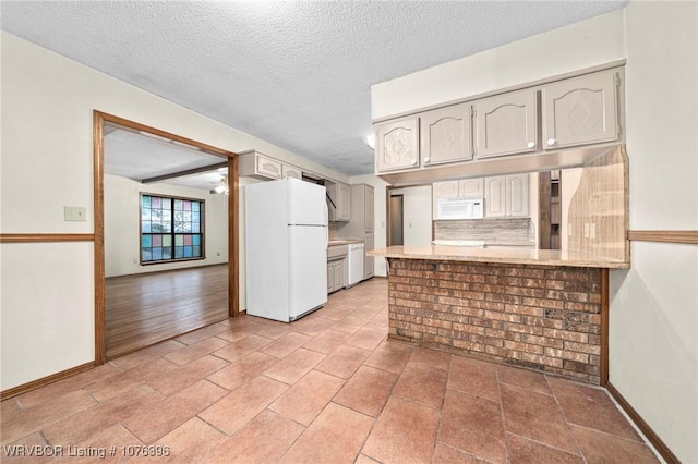 kitchen featuring backsplash, white appliances, kitchen peninsula, and a textured ceiling