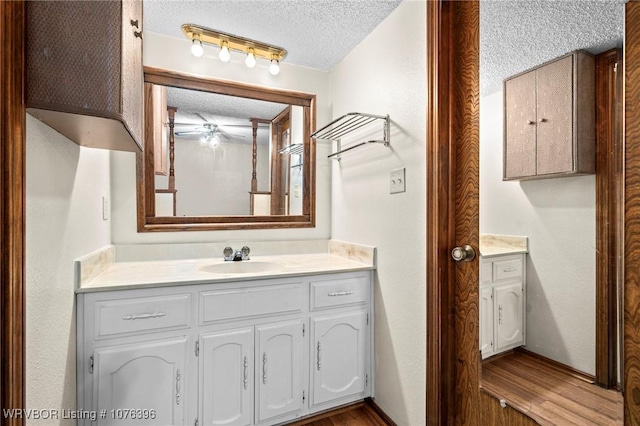 bathroom with vanity, wood-type flooring, a textured ceiling, and ceiling fan