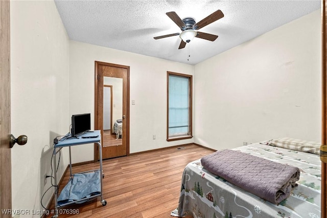 bedroom with ceiling fan, a textured ceiling, and light wood-type flooring