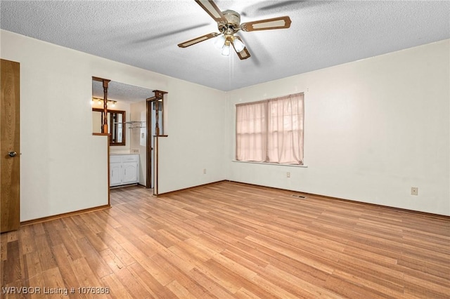 empty room featuring ceiling fan, light hardwood / wood-style floors, and a textured ceiling