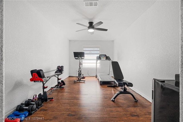 workout room featuring wood-type flooring, visible vents, ceiling fan, and baseboards