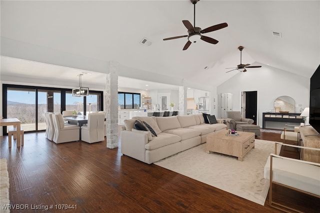 living area featuring dark wood-style floors, visible vents, high vaulted ceiling, and ceiling fan with notable chandelier