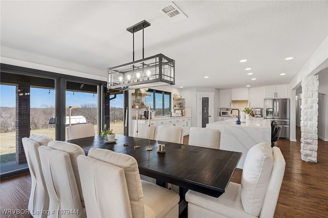 dining room with decorative columns, visible vents, dark wood-style flooring, and recessed lighting