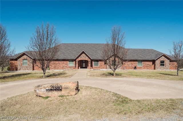 view of front of property featuring driveway, a front lawn, and a shingled roof