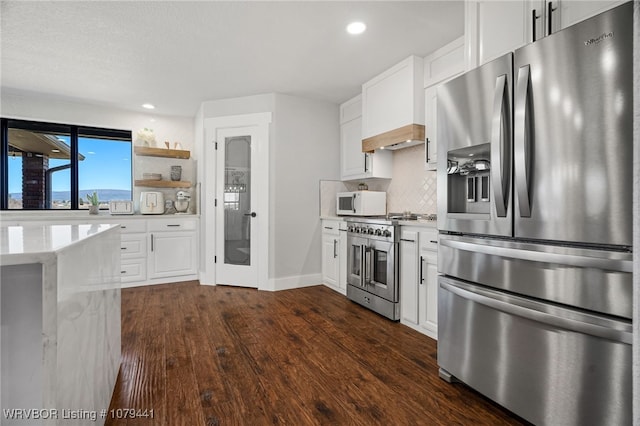 kitchen with dark wood finished floors, stainless steel appliances, custom range hood, decorative backsplash, and white cabinetry