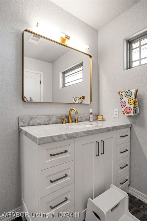 bathroom featuring a textured wall, baseboards, and vanity