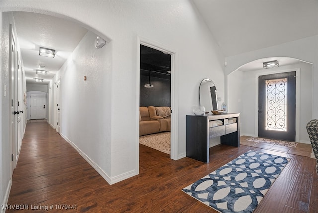 foyer featuring lofted ceiling, baseboards, arched walkways, and hardwood / wood-style floors