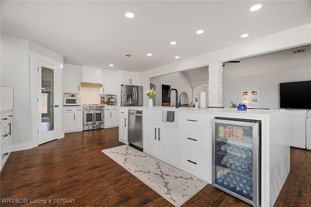 kitchen featuring visible vents, dark wood finished floors, wine cooler, appliances with stainless steel finishes, and light countertops