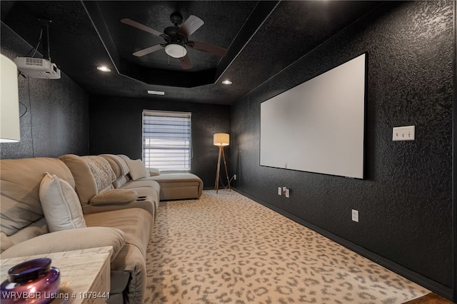 cinema featuring carpet floors, recessed lighting, a raised ceiling, a textured wall, and a ceiling fan