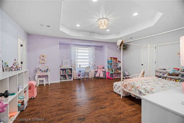 bedroom featuring a tray ceiling, visible vents, recessed lighting, and wood finished floors