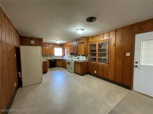 kitchen featuring light countertops, wood walls, brown cabinets, and white appliances