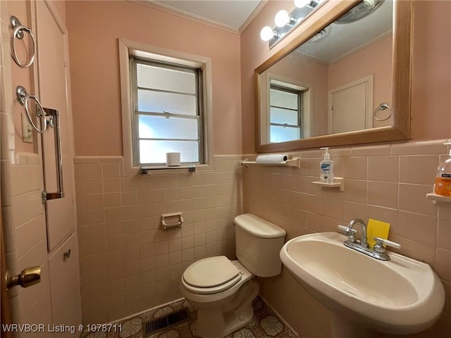 bathroom featuring crown molding, toilet, a sink, visible vents, and wainscoting