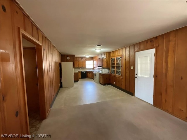 kitchen featuring wooden walls, brown cabinetry, finished concrete floors, and freestanding refrigerator