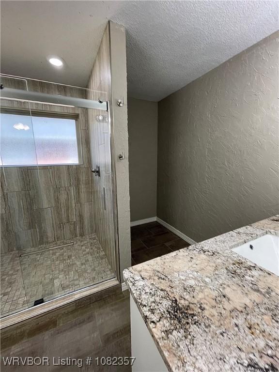 4104 Glen Flora Way, Fort Smith, AR 72908 - full bathroom featuring a textured wall, vanity, a shower stall, a textured ceiling, and tile patterned floors