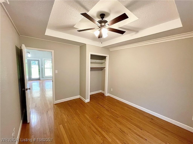 4104 Glen Flora Way, Fort Smith, AR 72908 - unfurnished bedroom with a tray ceiling, a textured ceiling, wood finished floors, a closet, and a ceiling fan
