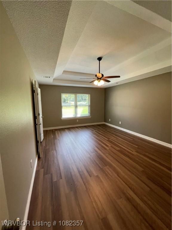 4104 Glen Flora Way, Fort Smith, AR 72908 - spare room featuring a raised ceiling, dark wood-type flooring, a ceiling fan, and a textured ceiling