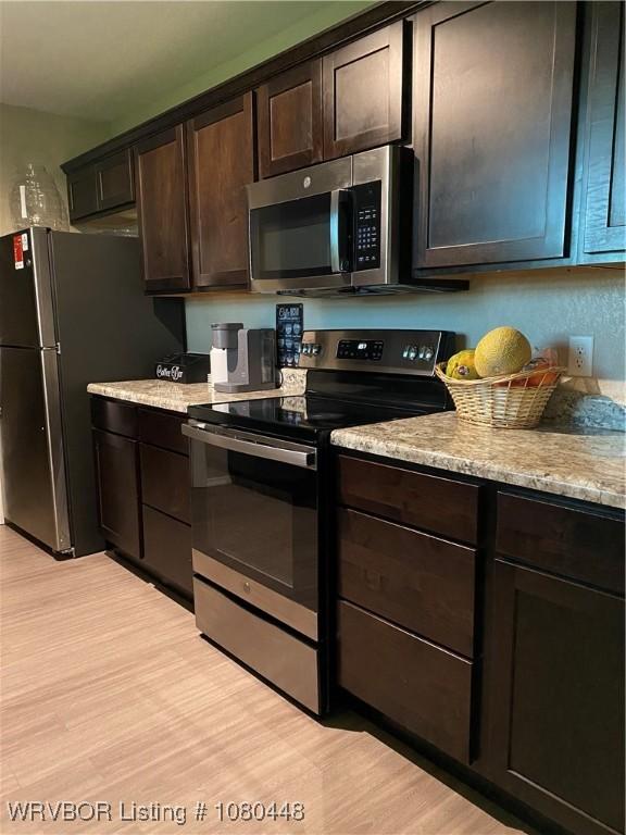1111 Bluebird Dr, Cedarville, AR 72932 - kitchen with light wood-style floors, light stone countertops, dark brown cabinets, and stainless steel appliances