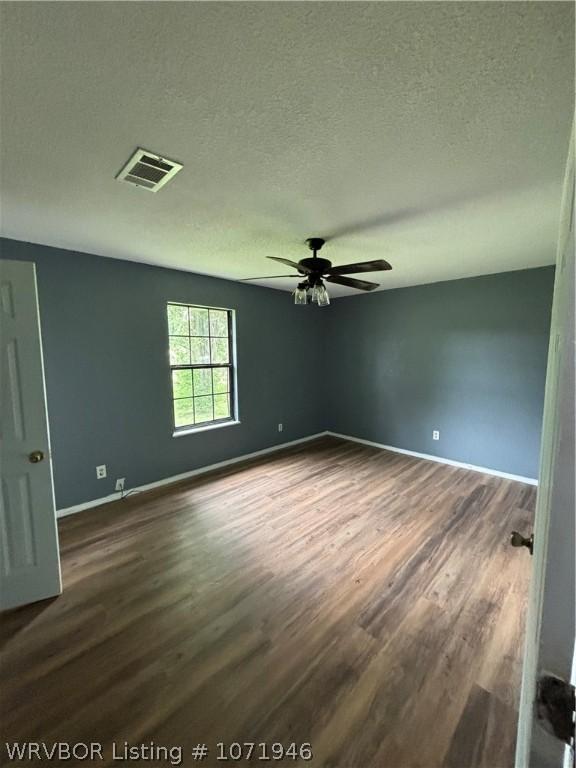 unfurnished room with ceiling fan, dark wood-type flooring, and a textured ceiling