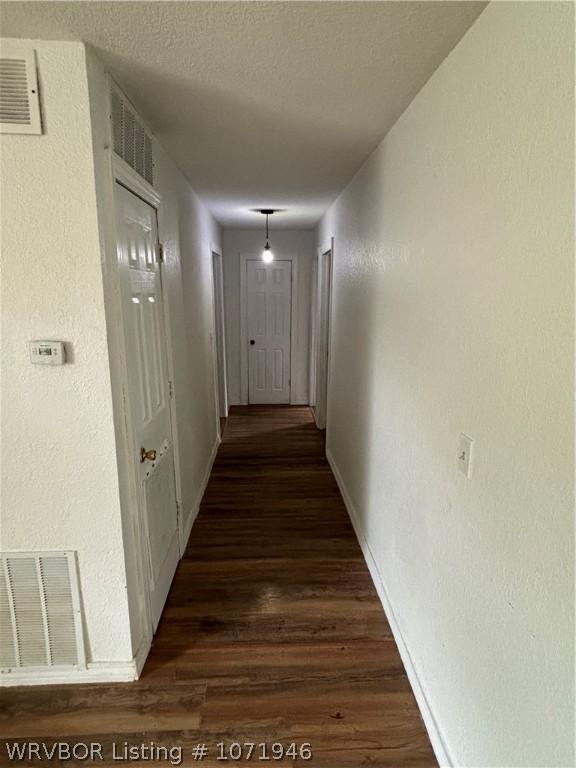 hall featuring a textured ceiling and dark hardwood / wood-style flooring