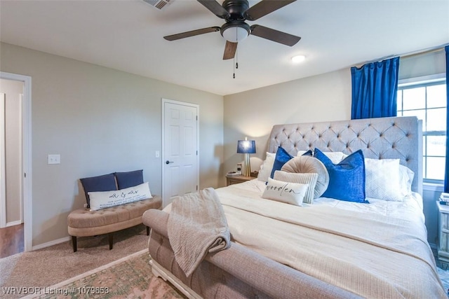 carpeted bedroom with visible vents, baseboards, and ceiling fan