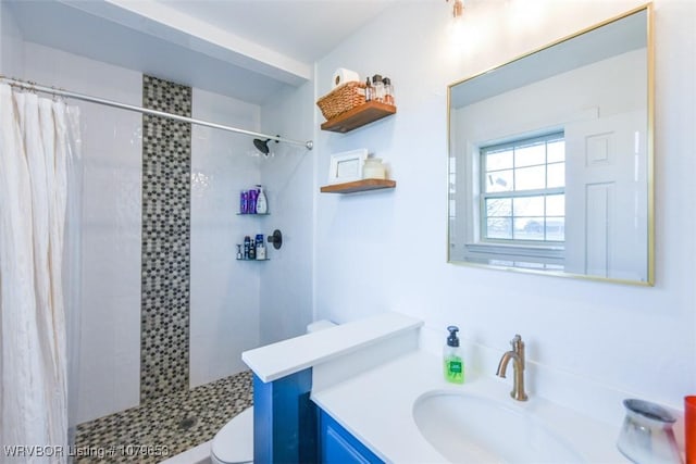 bathroom featuring vanity, toilet, and a tile shower