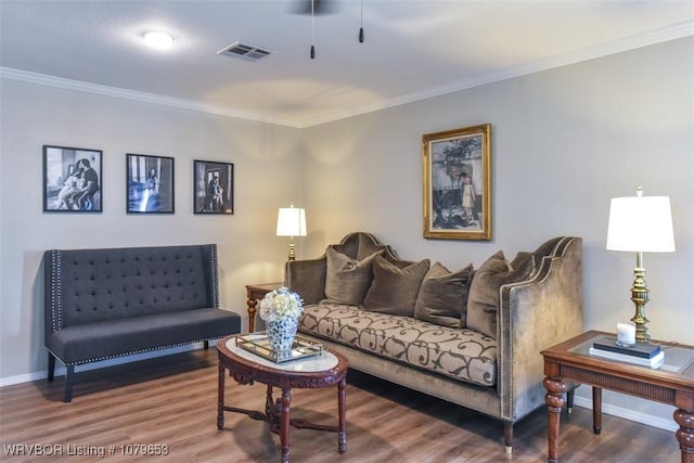 living room featuring baseboards, wood finished floors, visible vents, and ornamental molding