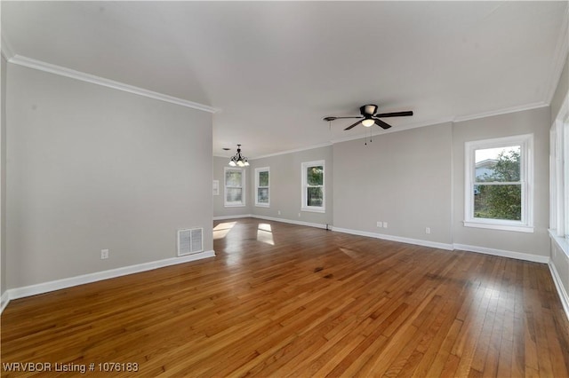 unfurnished living room with a healthy amount of sunlight, ornamental molding, ceiling fan with notable chandelier, and hardwood / wood-style flooring